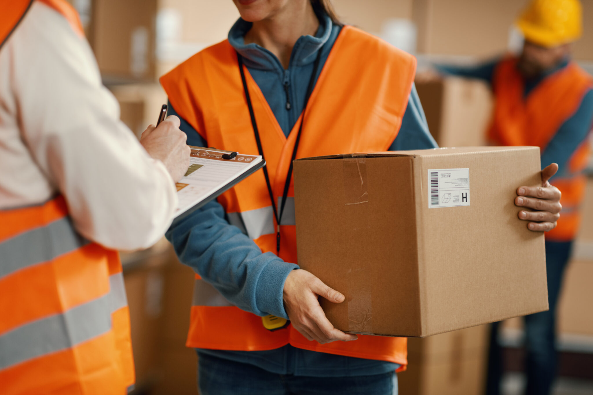 Person in safety vest holding a box